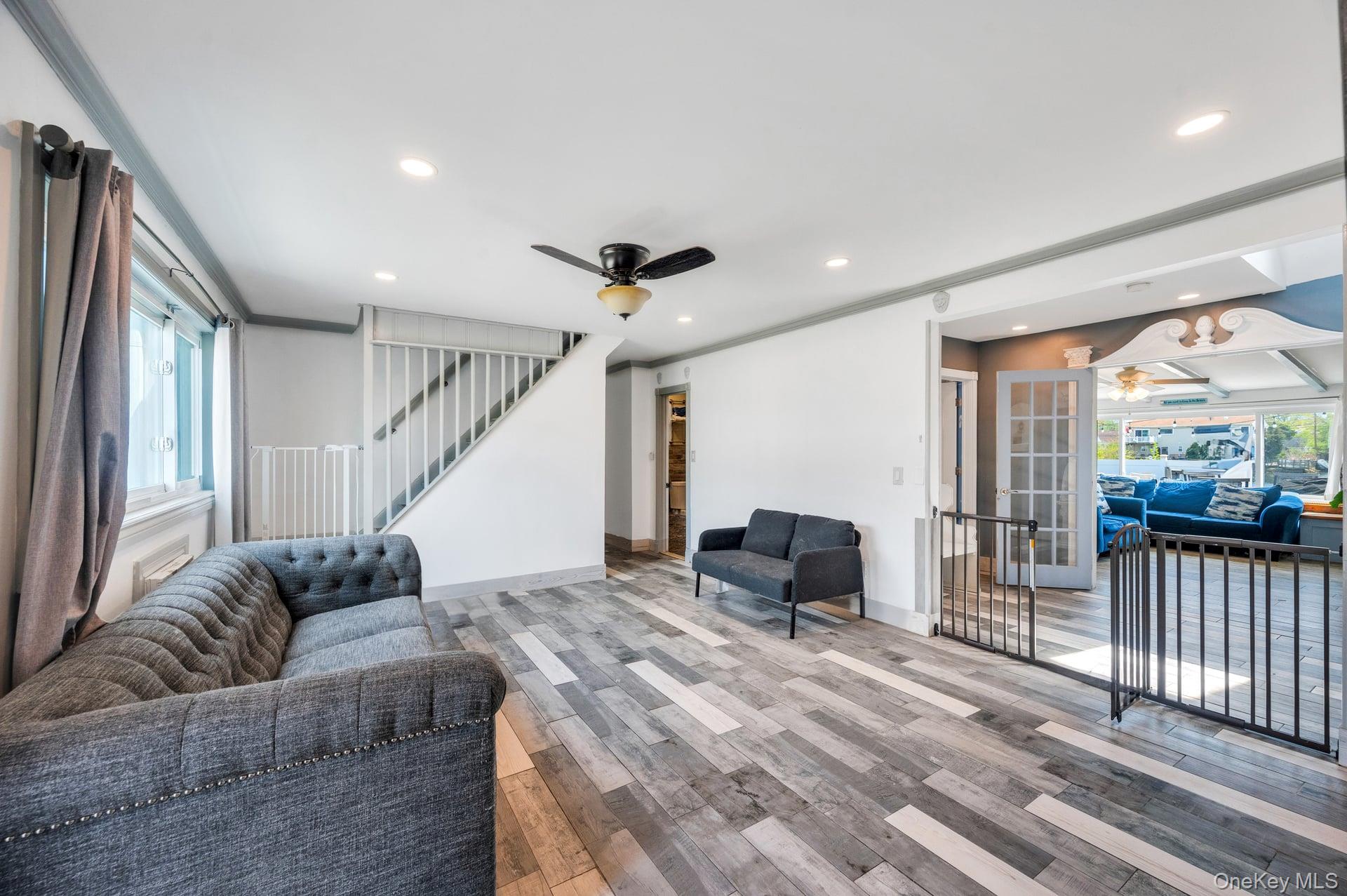 24 Raynor Street West Babylon, NY 11704 - Photo 9 of 45 Living room featuring a ceiling fan, light wood-style flooring, recessed lighting, stairway, and crown molding