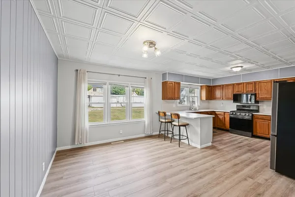 a kitchen with stainless steel appliances granite countertop a stove top oven a sink dishwasher a dining table and chairs with wooden floor