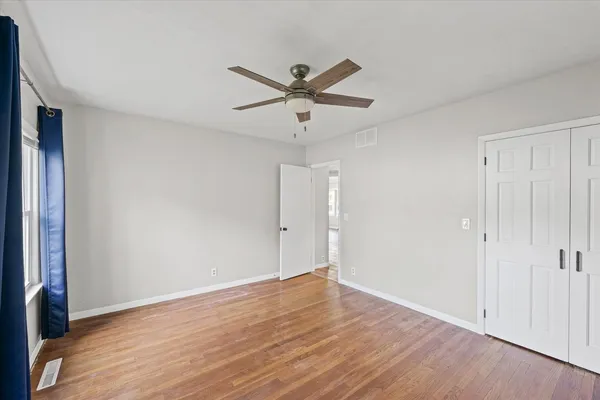 a view of a room with wooden floor and a ceiling fan