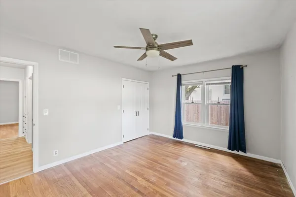 a view of empty room with wooden floor and fan