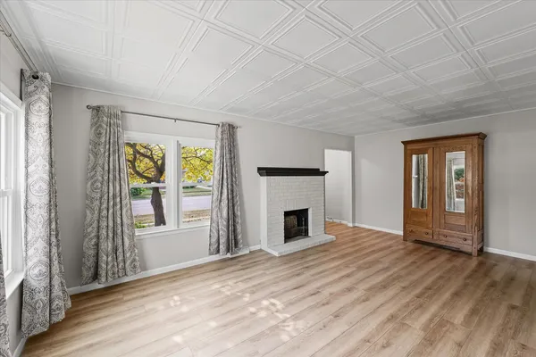 an empty room with windows fireplace and wooden floor