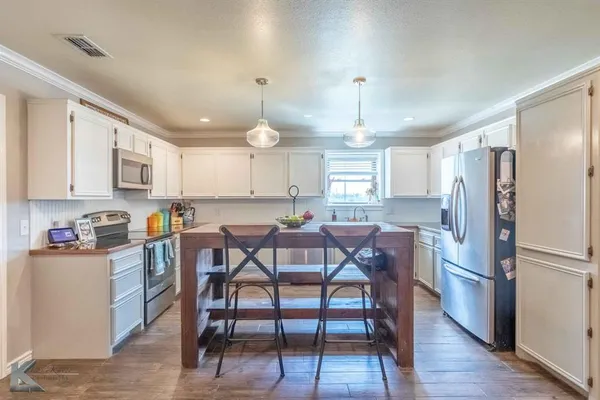 a kitchen with stainless steel appliances a dining table chairs refrigerator and sink
