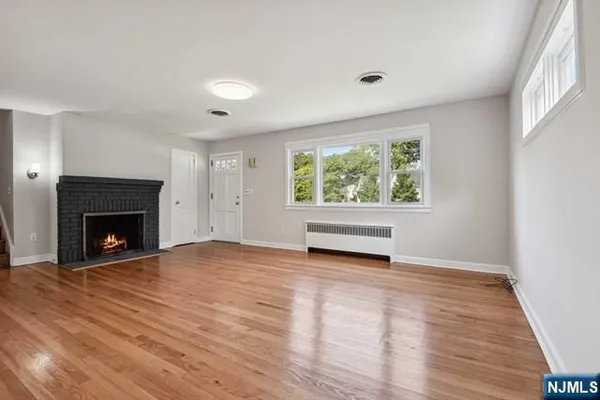 a view of empty room with wooden floor and fireplace