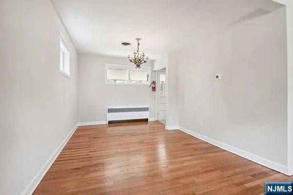 a view of an empty room with wooden floor and chandelier