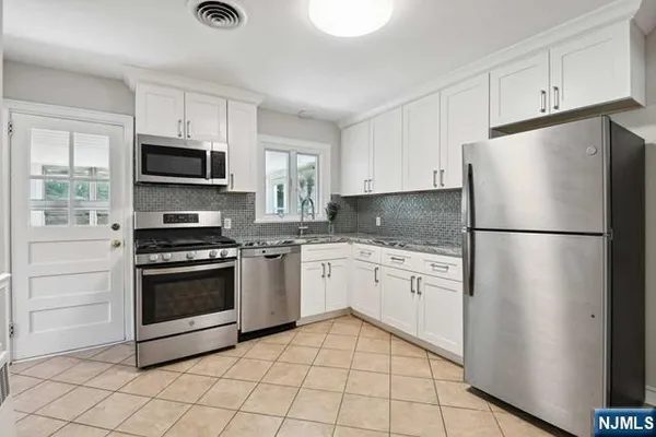 a kitchen with granite countertop a refrigerator stove and microwave