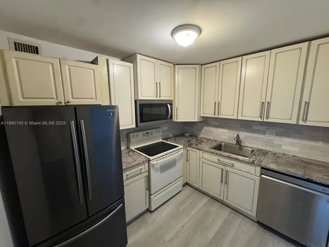 a kitchen with stainless steel appliances granite countertop a refrigerator sink and cabinets