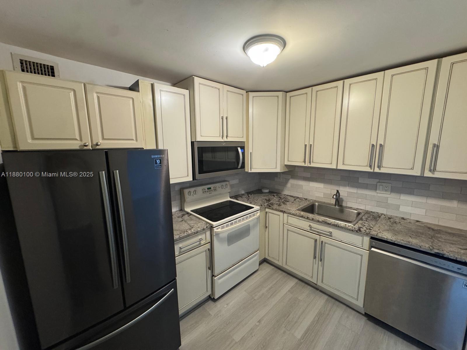 a kitchen with stainless steel appliances granite countertop a refrigerator sink and cabinets