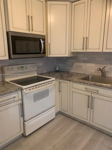 a kitchen with granite countertop white cabinets and white appliances