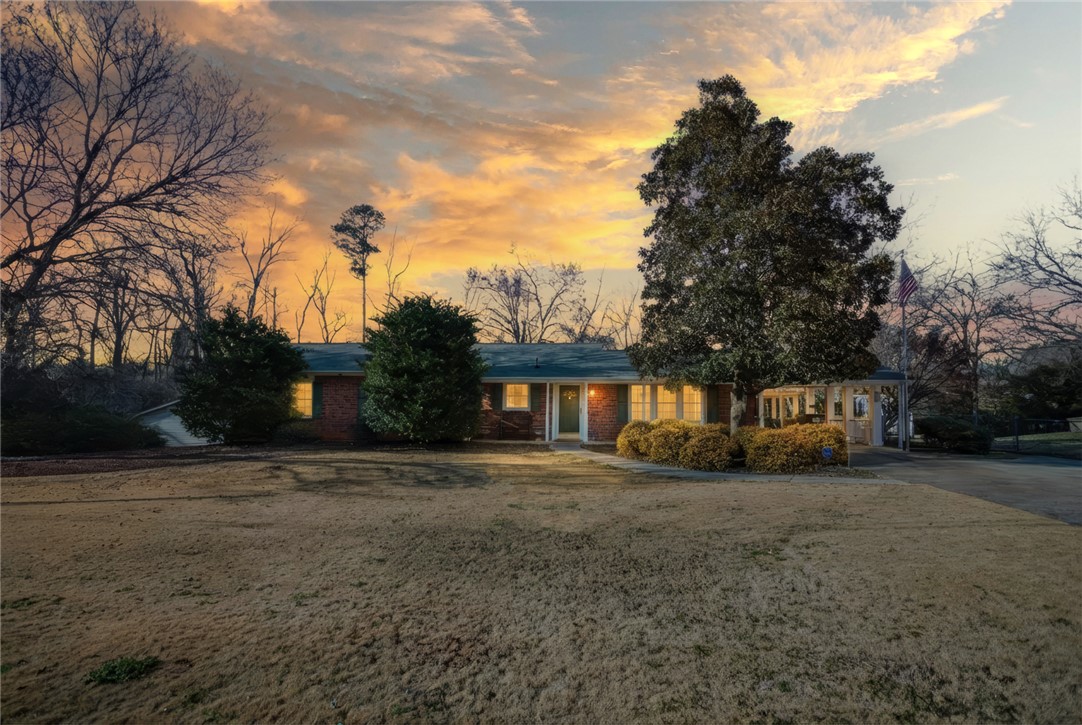 This charming residence is nestled among mature trees under a vibrant sky.