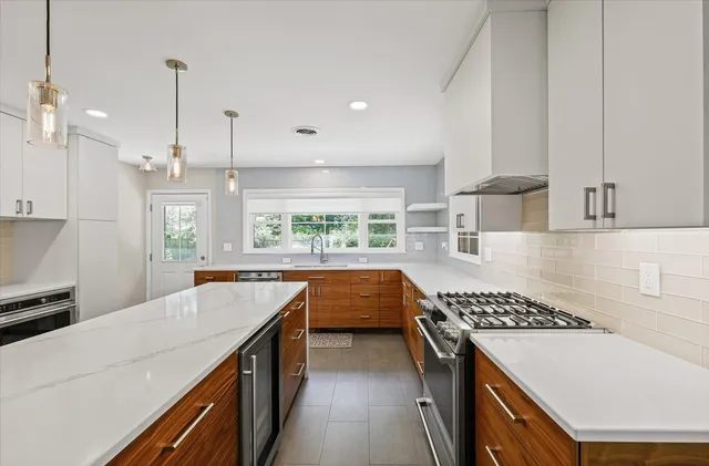 a kitchen with kitchen island a stove a sink a counter top space and cabinets