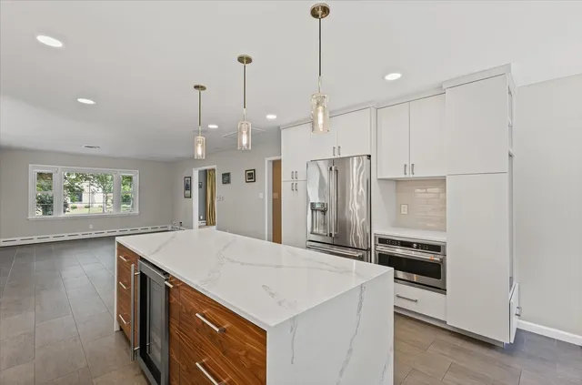 a kitchen with stainless steel appliances kitchen island a stove a sink a refrigerator and chairs