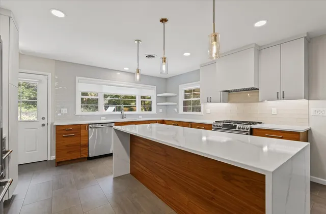 a large kitchen with stainless steel appliances granite countertop a sink a stove and a refrigerator