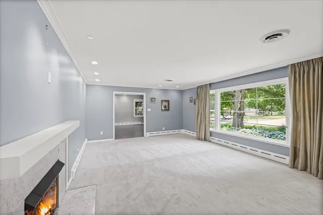 a view of an empty room with a window and a kitchen