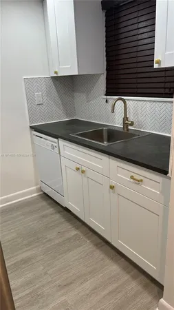 a kitchen with granite countertop white cabinets and sink