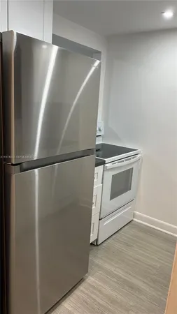 a view of a refrigerator in kitchen and stainless steel appliances wooden floor