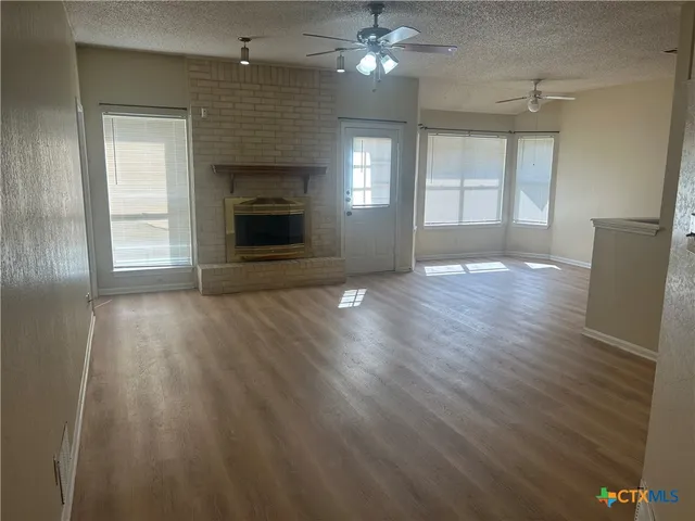 an empty room with wooden floor fireplace and windows