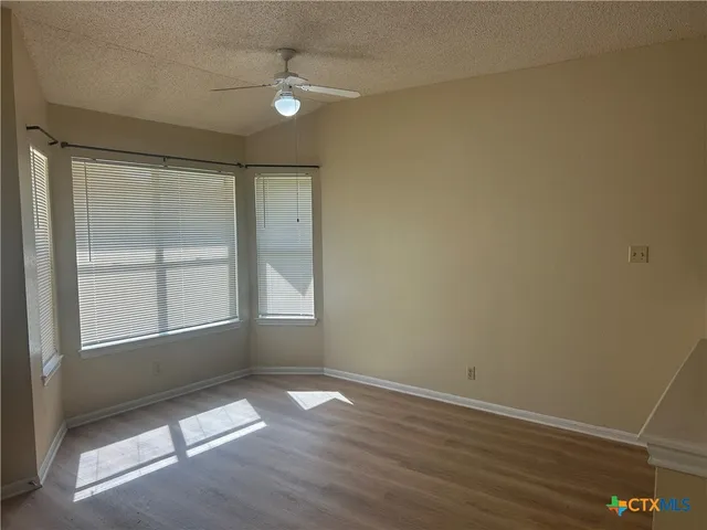 an empty room with wooden floor and windows