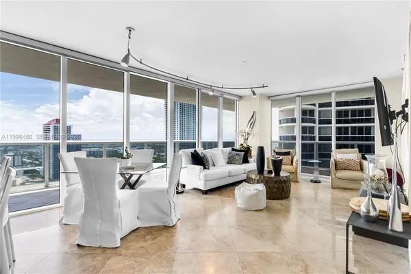 a living room with couches and kitchen view with wooden floor