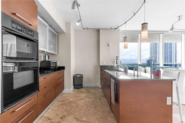 a living room with stainless steel appliances kitchen island granite countertop a table chairs and a view of living room
