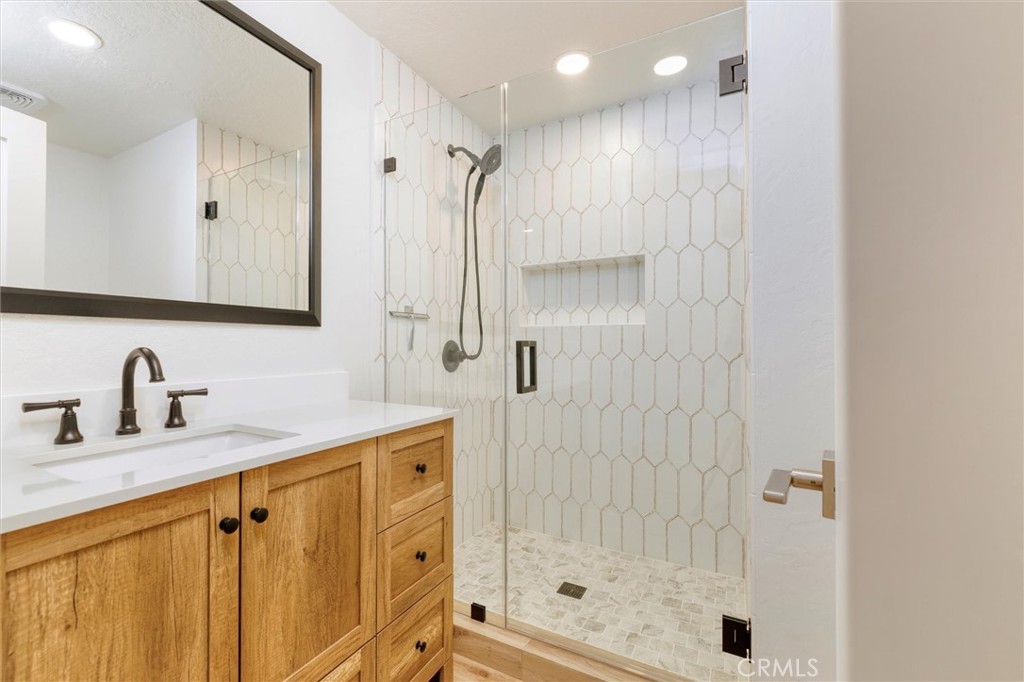 27139 Rio Prado Drive Valencia, CA 91354 - Photo 22 of 34 a bathroom with a granite countertop sink a mirror a shower and a shower