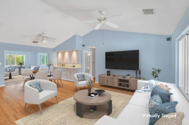 an empty room with wooden floor chandelier fan and windows