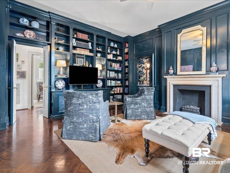 109 Eaton Square Mobile, AL 36608 - Photo 3 of 26 Wood-finish parquet flooring grounds this room featuring extensive built-in shelving, ornate crown molding, and wainscoting