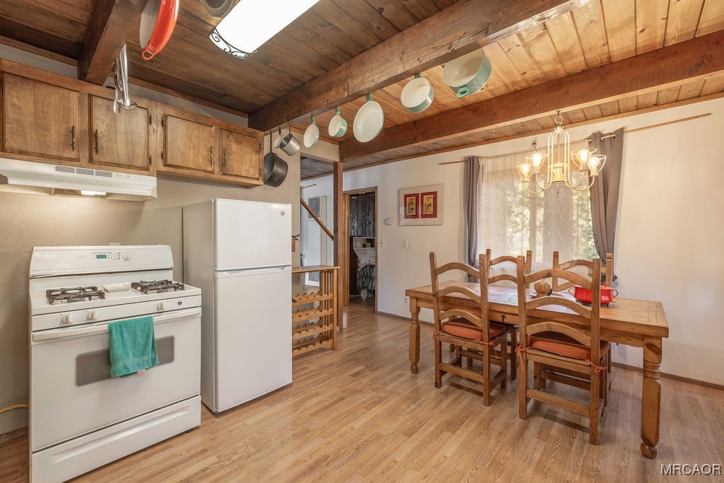 44185 Tim Ron Sugarloaf, CA 92386 - Photo 12 of 45 a kitchen with stainless steel appliances a stove a refrigerator a dining table and chairs with wooden floor