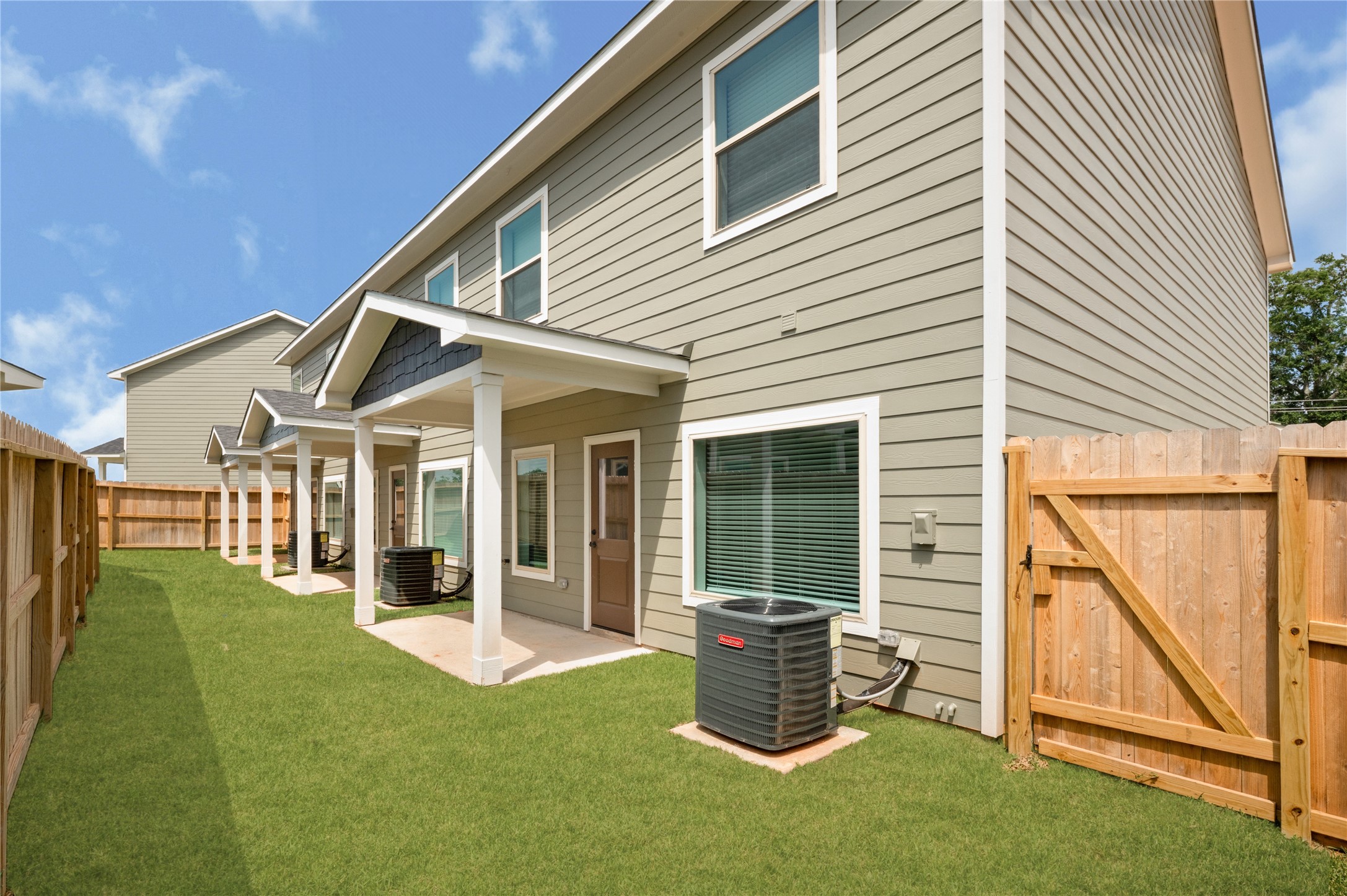 14010 Longstreet Road, Unit 2 Willis, TX 77318 - Photo 28 of 29 This photo shows the backyard of a modern two-story home with a fenced yard. It features a covered patio, well-maintained lawn, and outdoor HVAC unit. The exterior has neutral siding and multiple windows, offering a clean and inviting space.