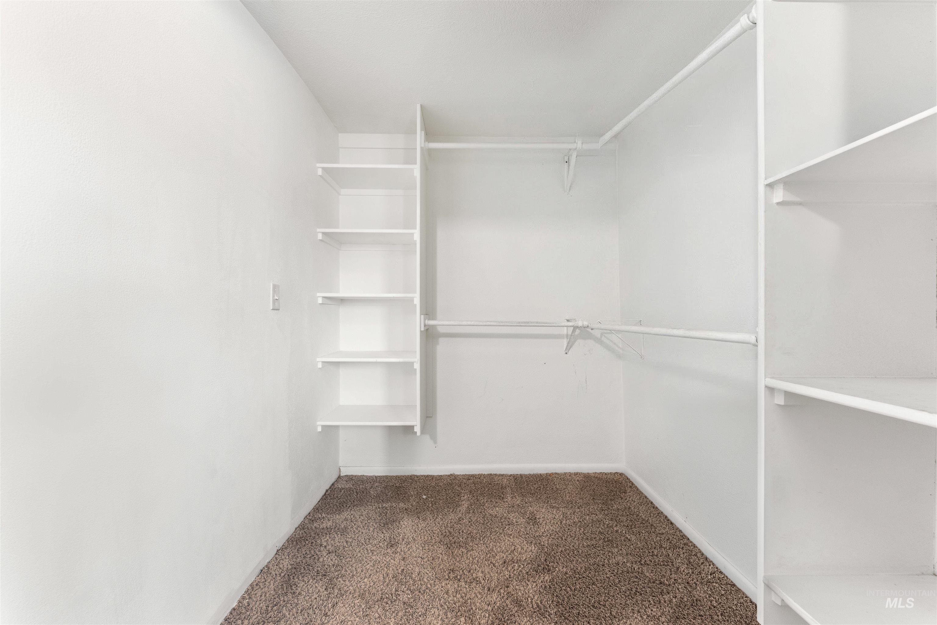17441 Upper Pleasant Ridge Road Caldwell, ID 83607 - Photo 25 of 40 Walk-in closet featuring built-in shelving, white walls, and brown carpet flooring