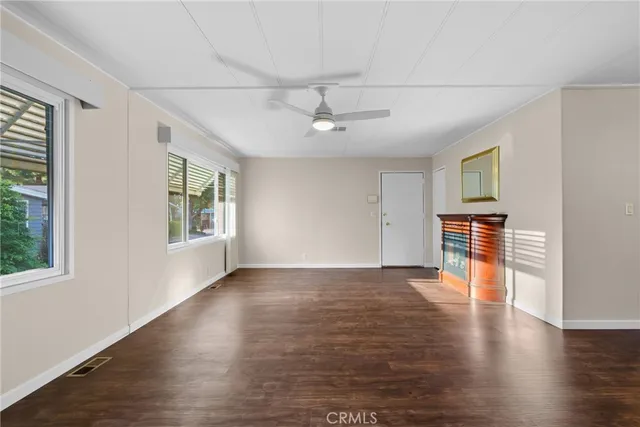 an empty room with wooden floor chandelier fan and windows