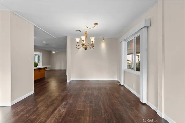 a view of a hallway with wooden floor and a chandelier