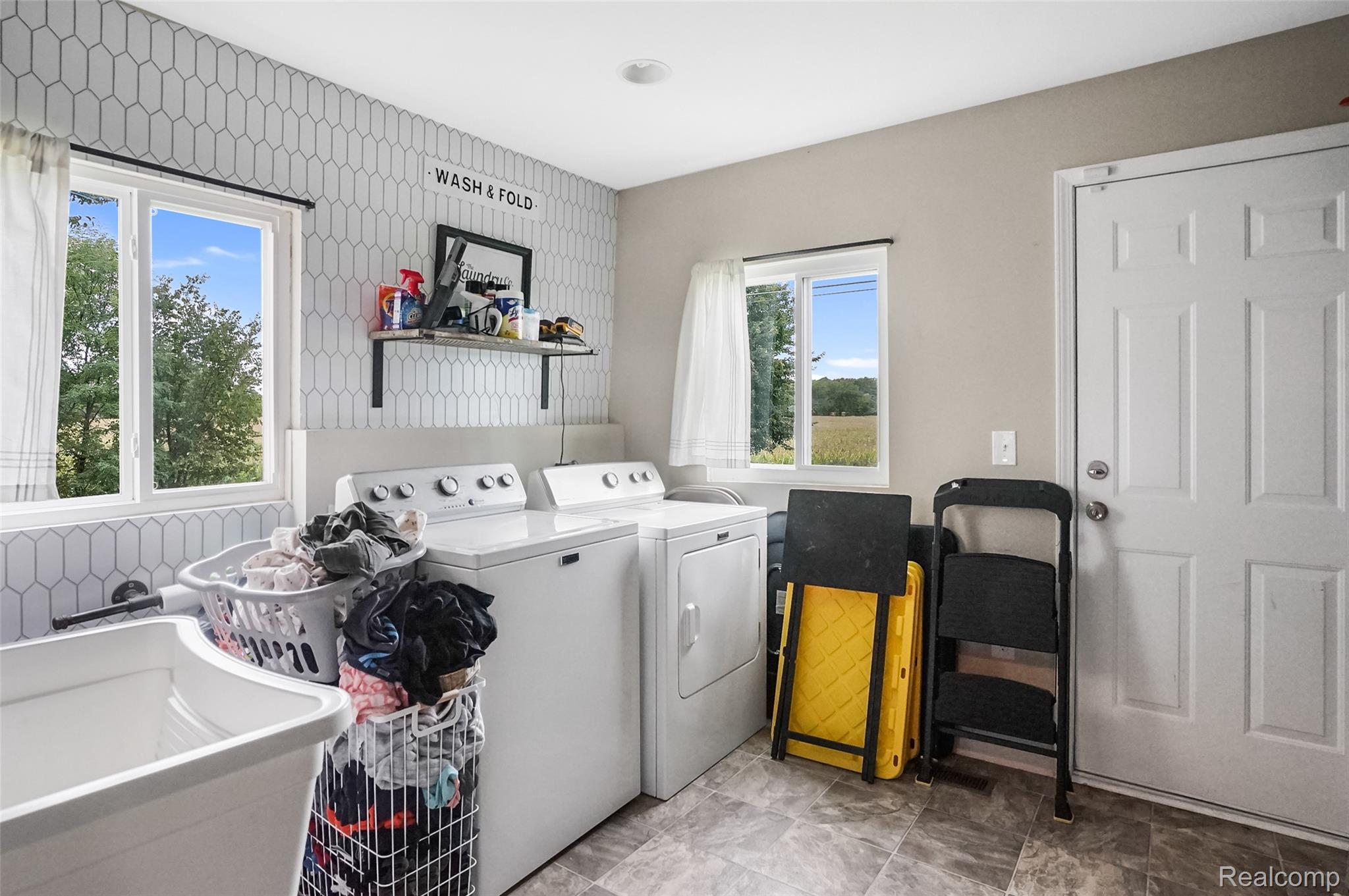 8330 Baldwin Road Gaines, MI 48436 - Photo 19 of 27 Laundry area with two windows, a utility sink, patterned wall tile, and a permanent shelving unit