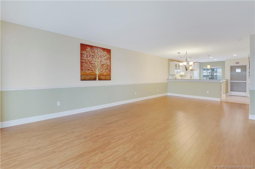 1864 Southwest Palm City Road, Unit 202 Stuart, FL 34994 - Photo 7 of 29 an empty room with wooden floor and chandelier
