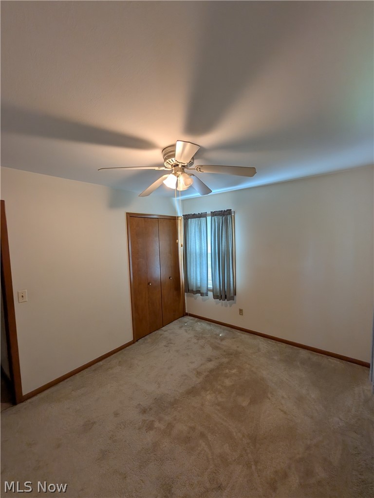 1161 Gulf Road Elyria, OH 44035 - Photo 17 of 34 Carpeted interior room featuring a ceiling fan with integrated lighting, wood-finish closet doors, and a window with drapery