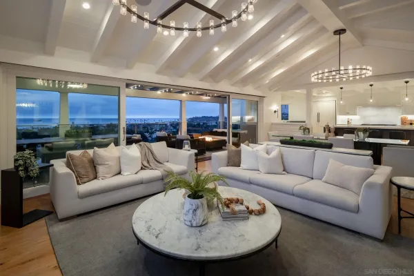 a living room with furniture kitchen view and a chandelier