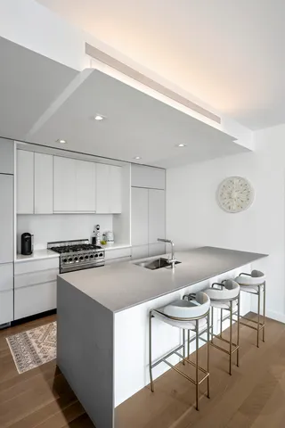 a kitchen with stainless steel appliances granite countertop a dining table chairs and a refrigerator