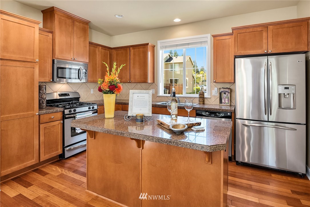 3617 183rd Place Southeast Bothell, WA 98012 - Photo 11 of 27 a kitchen with stainless steel appliances granite countertop a refrigerator a stove a sink dishwasher a refrigerator white cabinets and wooden floor