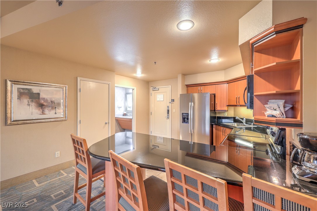 211 East Flamingo Road, Unit 1402 Las Vegas, NV 89169 - Photo 9 of 43 Kitchen featuring open shelves, stainless steel fridge, brown cabinetry, a textured ceiling, and a peninsula