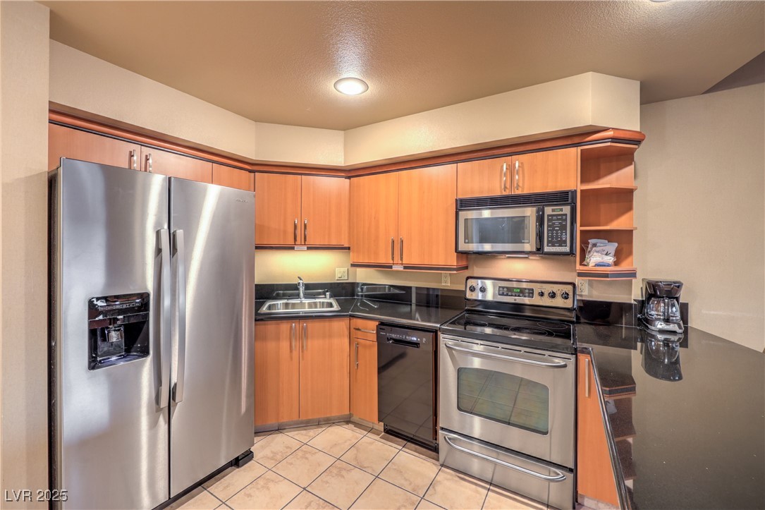 211 East Flamingo Road, Unit 1402 Las Vegas, NV 89169 - Photo 7 of 43 Kitchen featuring appliances with stainless steel finishes, open shelves, dark stone counters, a textured ceiling, and brown cabinets