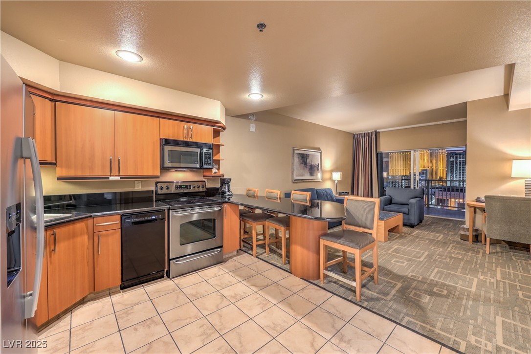 211 East Flamingo Road, Unit 1402 Las Vegas, NV 89169 - Photo 42 of 43 Kitchen featuring appliances with stainless steel finishes, brown cabinetry, open floor plan, open shelves, and a peninsula
