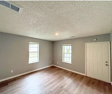 an empty room with wooden floor and windows