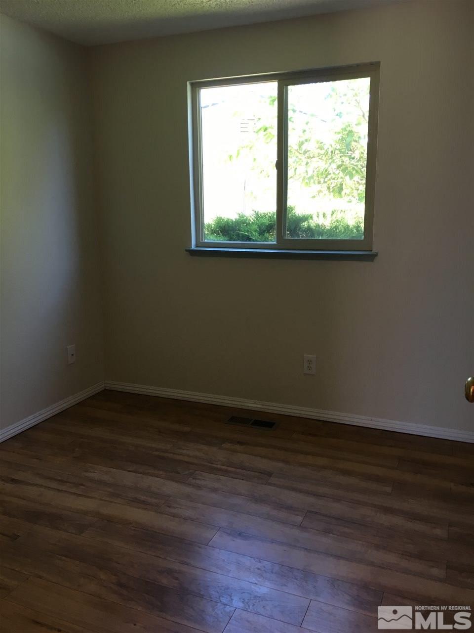 10003 Albite Street Reno, NV 89506 - Photo 13 of 25 a view of an empty room with wooden floor and a window