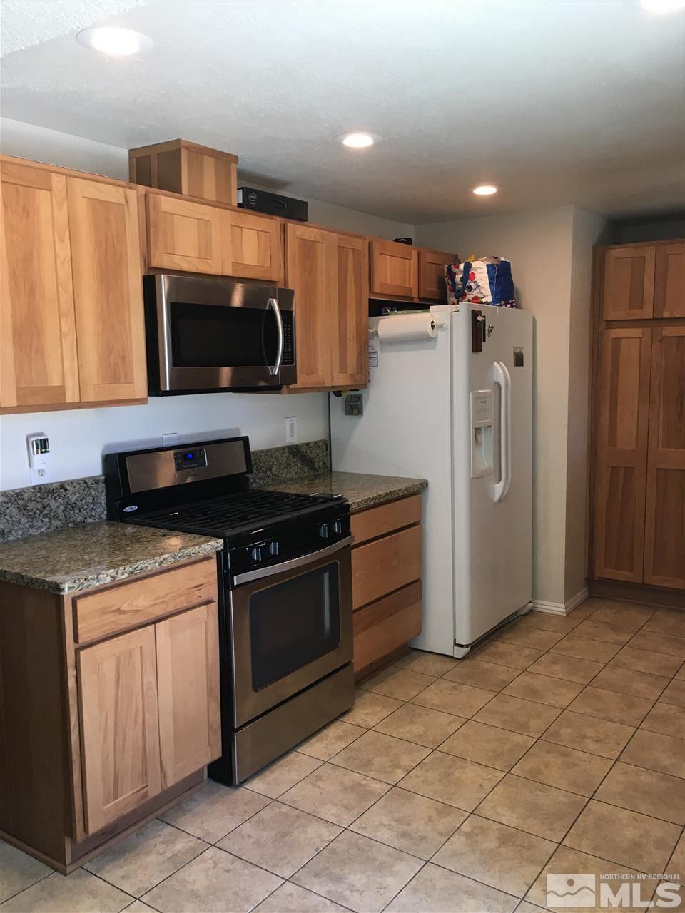 10003 Albite Street Reno, NV 89506 - Photo 22 of 25 a kitchen with stainless steel appliances granite countertop a stove a refrigerator and a microwave