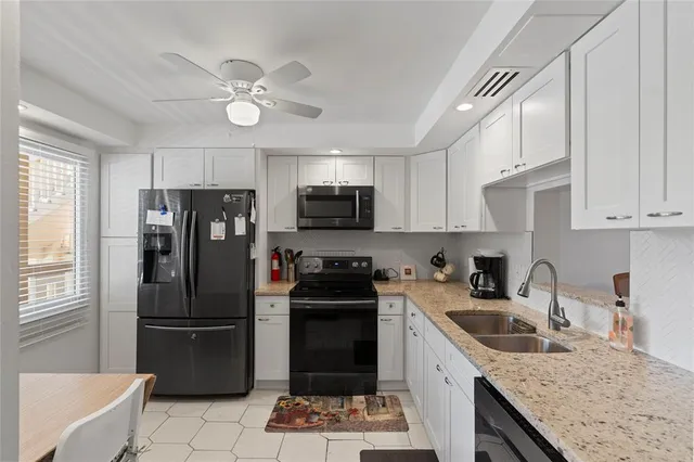 a kitchen with a sink stainless steel appliances and chandelier
