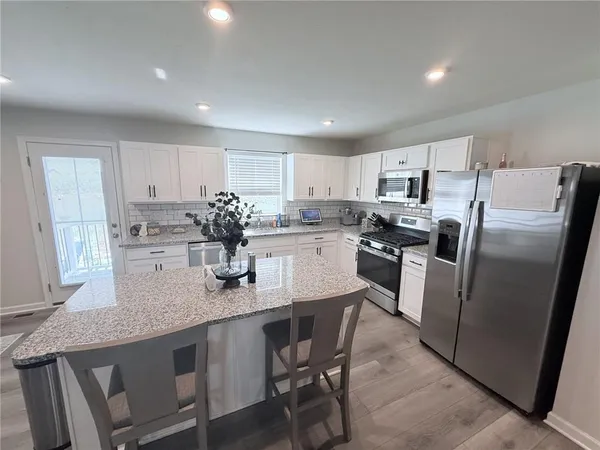 a kitchen with stainless steel appliances granite countertop a sink a stove a refrigerator with white cabinets
