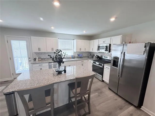 a kitchen with stainless steel appliances granite countertop a sink a stove a refrigerator with white cabinets