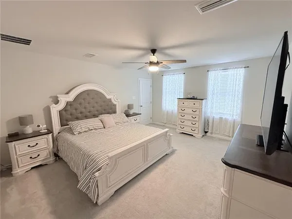a bedroom with a bed a large mirror and a flat tv screen on dresser