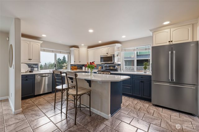 a kitchen with a sink a refrigerator and chairs