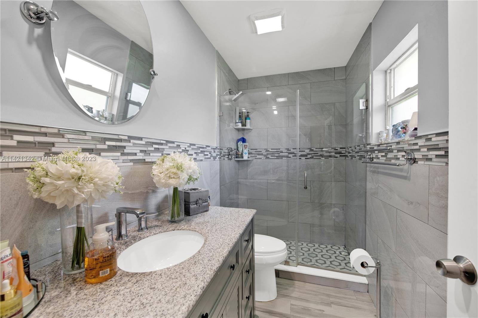 1480 Southwest 17th Street Naples, FL 34117 - Photo 22 of 36 a bathroom with a granite countertop sink a toilet a mirror and shower
