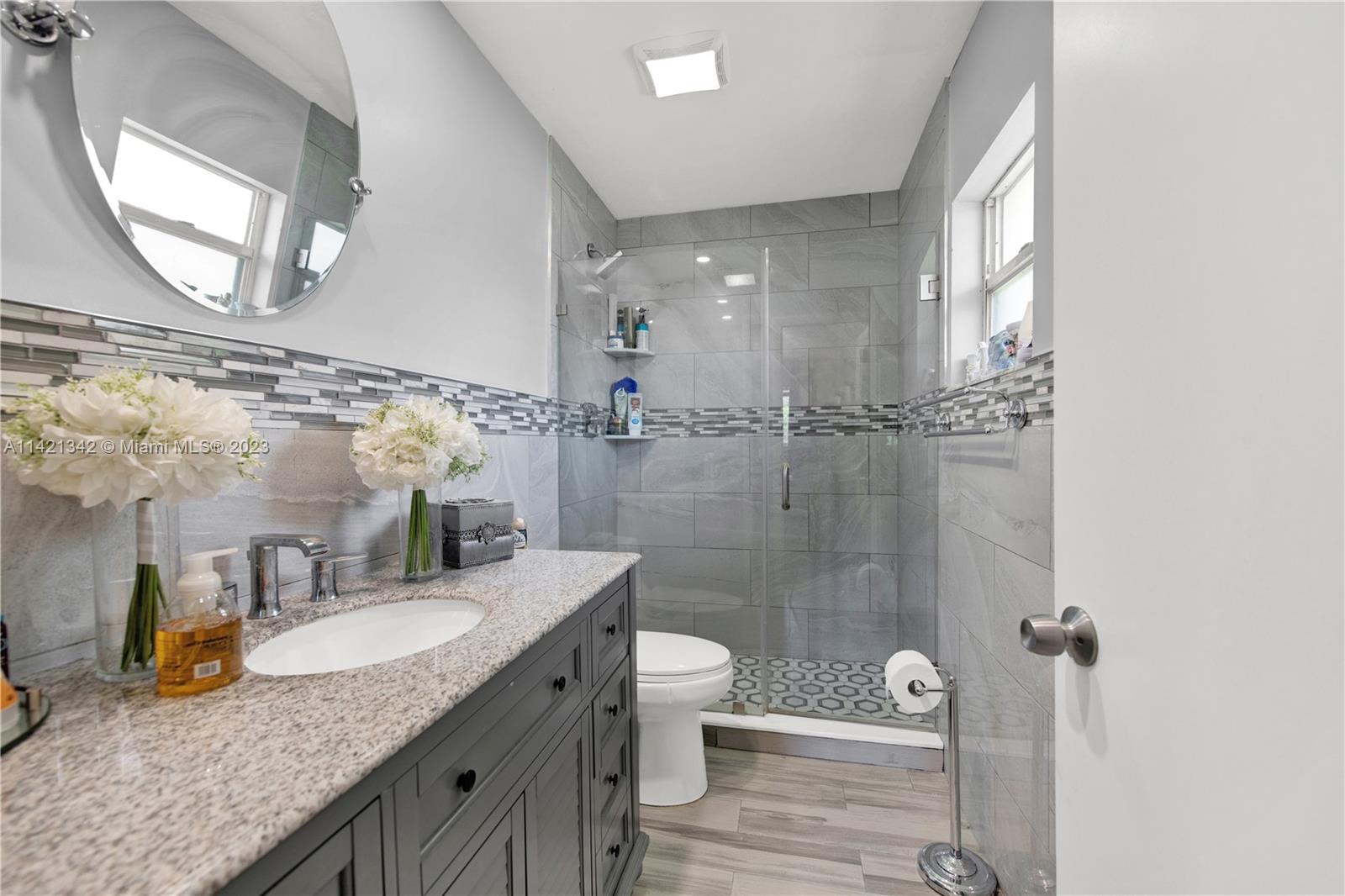 1480 Southwest 17th Street Naples, FL 34117 - Photo 23 of 36 a bathroom with a granite countertop sink a toilet a mirror and shower